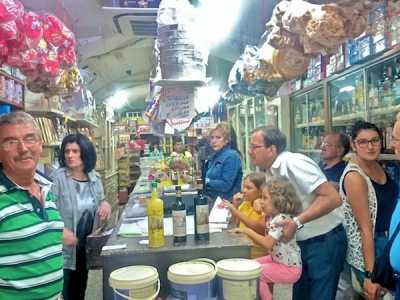 All'interno del locale moltissimi clienti fanno la fila per comprare leccornie di ogni genere sotto lo sguardo di Vito, uno dei proprietari, qui immortalato in primo piano a sinistra