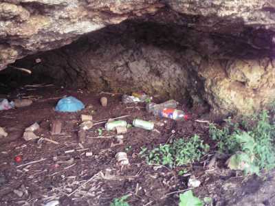 Interno di una grotta a cala Colombo, piena di rifiuti