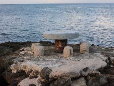 Un tavolo con delle sedie in cemento posto a ridosso del mare, a San Domenico
