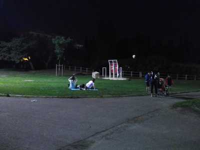 Sulla sinistra un gruppo di ragazze distese sui tappetini si gode la tranquillit� del parco di sera