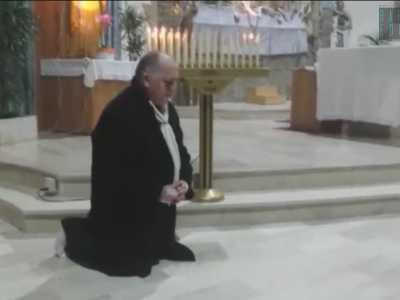 Il prete invita l'uomo a pregare in ginocchio davanti a tutti i fedeli