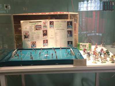 Un album di figurine stampato negli anni 70 posto dietro il microcalcio, una specie di Subbuteo del 1950 in cui i giocatori vengono mossi con delle manopole installate dietro le porte