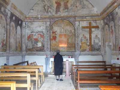 Una fedele in preghiera davanti all'affresco dell'Annunciazione, all'interno della chiesetta dell'Annunziata