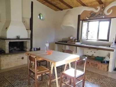 La cucina e sala da pranzo della casa in paglia. Sullo sfondo si nota la cappa artigianale, la cui struttura interna � fatta di rami di ulivo intrecciati e ricoperti di terra e calce