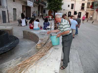 Gaetano si aiuta con dell�acqua con cui inumidisce la paglia in modo da renderla pi� malleabile