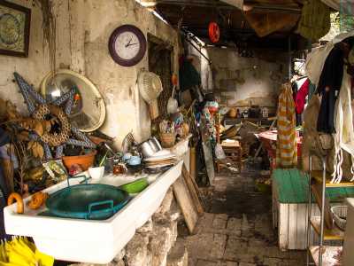Sotto una pensilina si nasconde la verandina coperta che precede l�ingresso in casa. La zona funge da cucina e tra un lavello, un vecchio tavolo e un carello, giacciono ammassati ogni tipo di stoviglia, orologi, specchi opachi, indumenti logori 