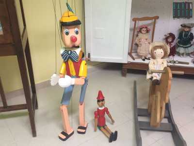 Due esemplari di Pinocchio accanto a un cavallo a dondolo