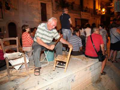 Gaetano con un piccolo bastone che picchia sulla sedia a lavoro finito per rendere la seduta pi� stabile