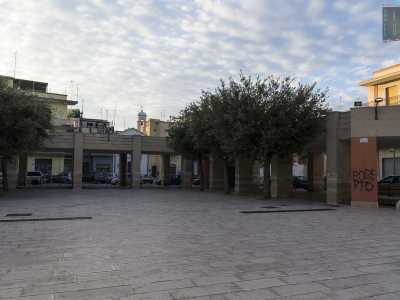 Giungiamo nel cuore del rione: piazza Antonio Gramsci, dominata da un anonimo porticato a ferro di cavallo che accoglieva fino a qualche anno fa il mercato comunale