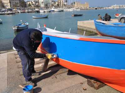 Un pescatore mentre dipinge la sua barca 