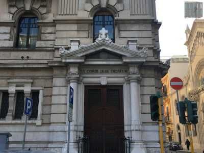 Il portone della chiesa del Sacro Cuore con il suo cancelletto nero e le due colonne laterali che sorreggono il timpano sul quale svetta una croce in marmo