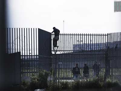 I migranti scavalcano il cancello del Cara per raggiungere gli autobus di linea dato che i pullman del centro non sono sufficienti