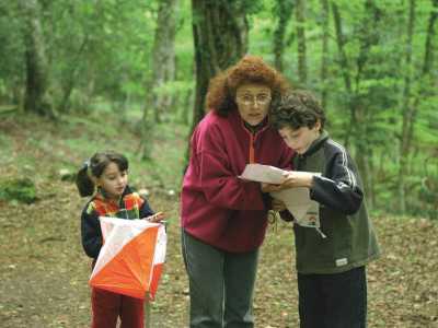 Una donna e due bambini, probabilmente madre e figli, fermi a un punto di controllo consultano la mappa