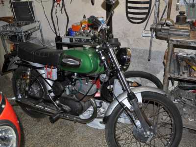 Accanto si trova una Aermacchi Harley Davidson verde e nera del 1974 