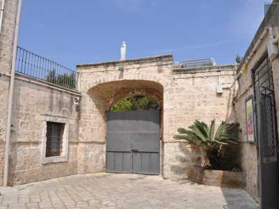 ...e un grande cancello metallico sovrastato da una statuetta della Madonna che chiude il cortile