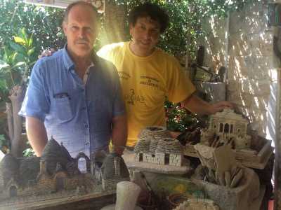 I due artigiani Giuseppe Maffei e Orazio Annese posano vicini ad alcuni trulli ancora da ultimare