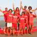 Un gruppo di bagnini sulla spiaggia con la barca a remi e il salvagente di salvataggio 
