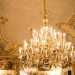 ...e dai due lampadari di cristallo. Questi ultimi pendono da un soffitto con motivo a intreccio e putti che sorreggono vari stemmi