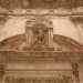 Il tutto  sormontato da un architrave con il timpano interrotto da una nicchia che racchiude la statua dell'Arcangelo Gabriele, attorniato naturalmente da teschi e ossa