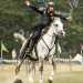 Un arciere a cavallo con in mano un arco mediorientale durante una sessione di caccia