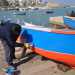 Un pescatore mentre dipinge la sua barca 