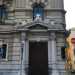 Il portone della chiesa del Sacro Cuore con il suo cancelletto nero e le due colonne laterali che sorreggono il timpano sul quale svetta una croce in marmo