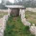 Alte pietre poste sul terreno formano un corridoio lungo 8 metri che ci introduce alla cella sepolcrale, composta da tre grandi lastroni verticali su cui poggia il lastrone di copertura. Il dolmen appare quindi chiuso da un lato