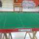 Un campo da gioco di Subbuteo con mini cartelli pubblicitari, recinzioni e alcuni tifosi